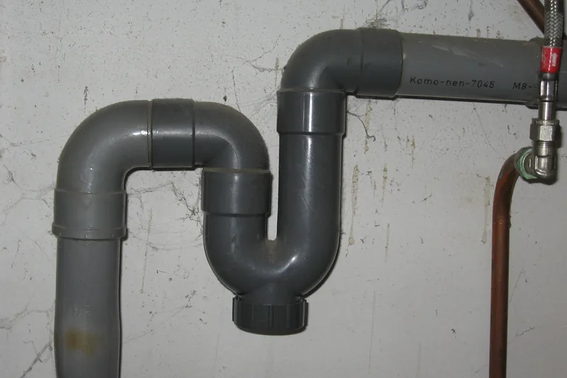 Sifón y tramo de desagüe visibles bajo un lavabo.